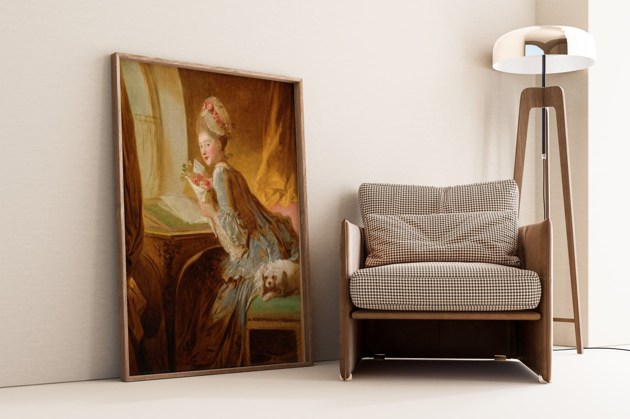 "The Love Letter" by Jean-Honoré Fragonard, displayed leaning against a wall in a modern room with a contemporary chair and lamp. The painting shows a woman in an elaborate blue gown, reading a letter by the window, accompanied by a small dog. Main colors are blue, gold, and soft pastels.