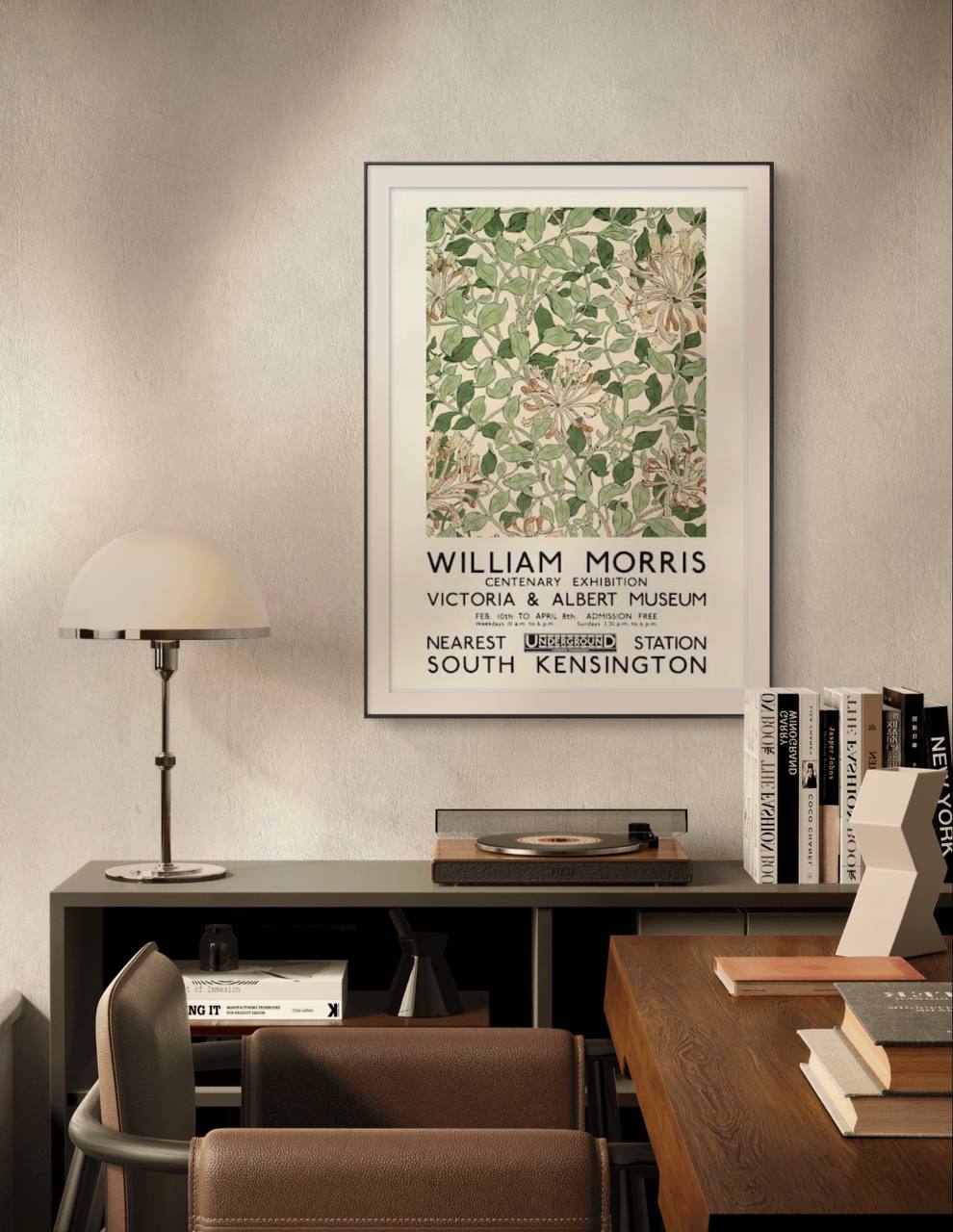 This William Morris exhibition poster is framed in white and gold, hanging in a modern home office. The intricate botanical design stands out against the minimalist room, adding a touch of vintage elegance.