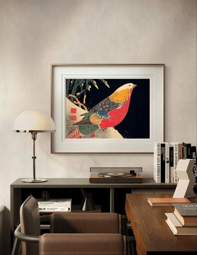 The framed "Golden Pheasant in the Snow" artwork hangs on a minimalist white wall, its bold colors and intricate details creating a striking focal point in the modern space.