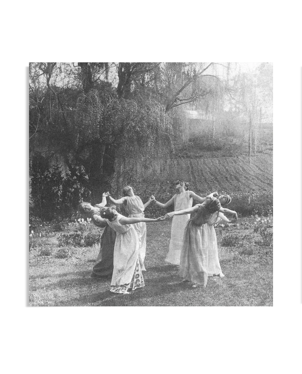 A vintage black-and-white photograph of women in flowing dresses dancing in a circle in a grassy field. Their graceful movements and serene surroundings evoke a sense of harmony with nature, reminiscent of a ritualistic gathering.