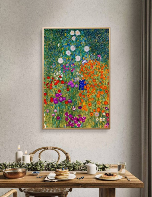 A framed painting of a colorful flower garden displayed above a dining table set with breakfast. The bright orange, purple, and red flowers in the painting contrast beautifully with the minimalist, natural decor of the dining area.