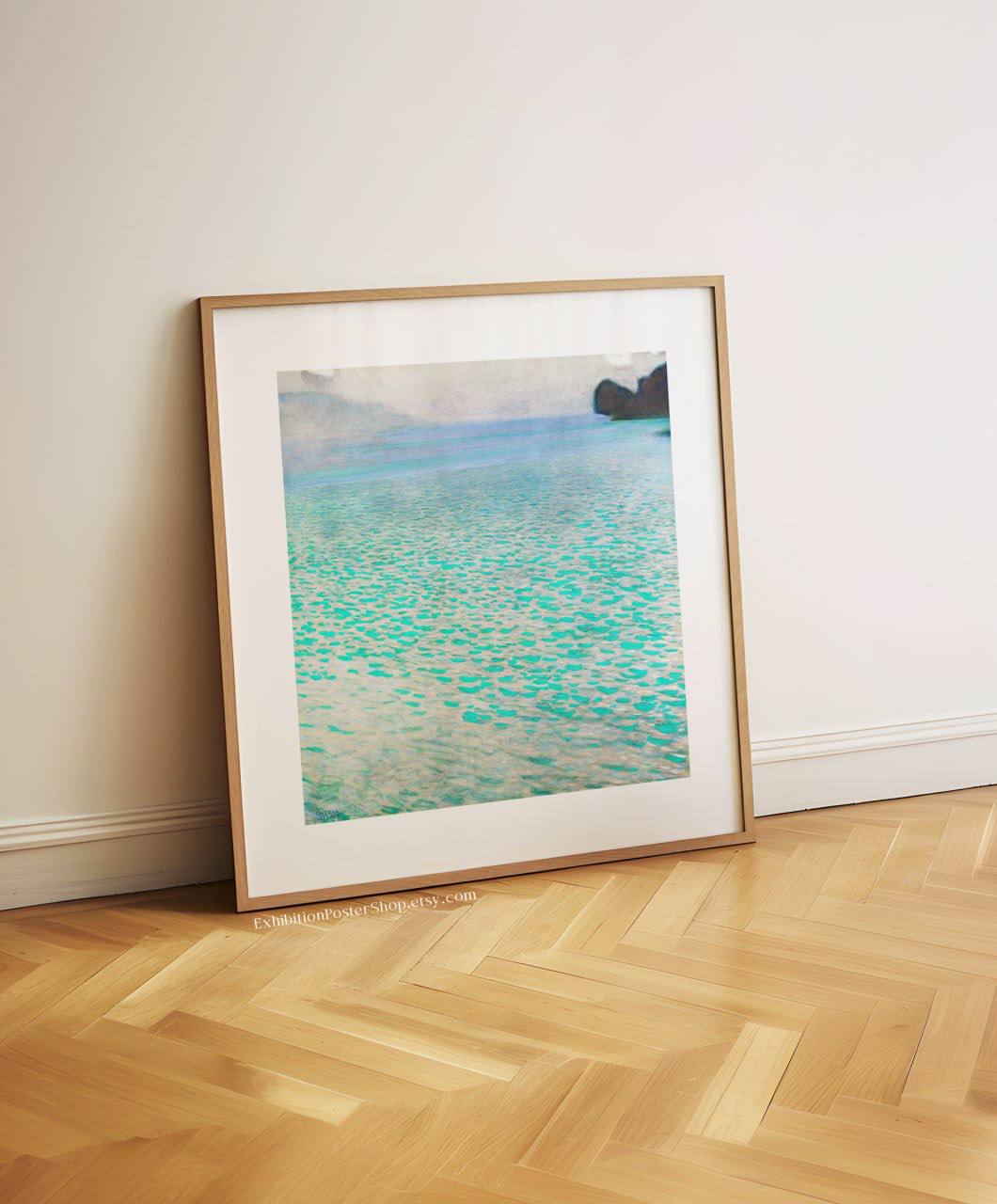 A framed painting of a peaceful lake scene, leaning against a white wall. The water's turquoise hues stand out, reflecting light beautifully, and the artwork's simplicity brings a calming effect to the minimalist space.