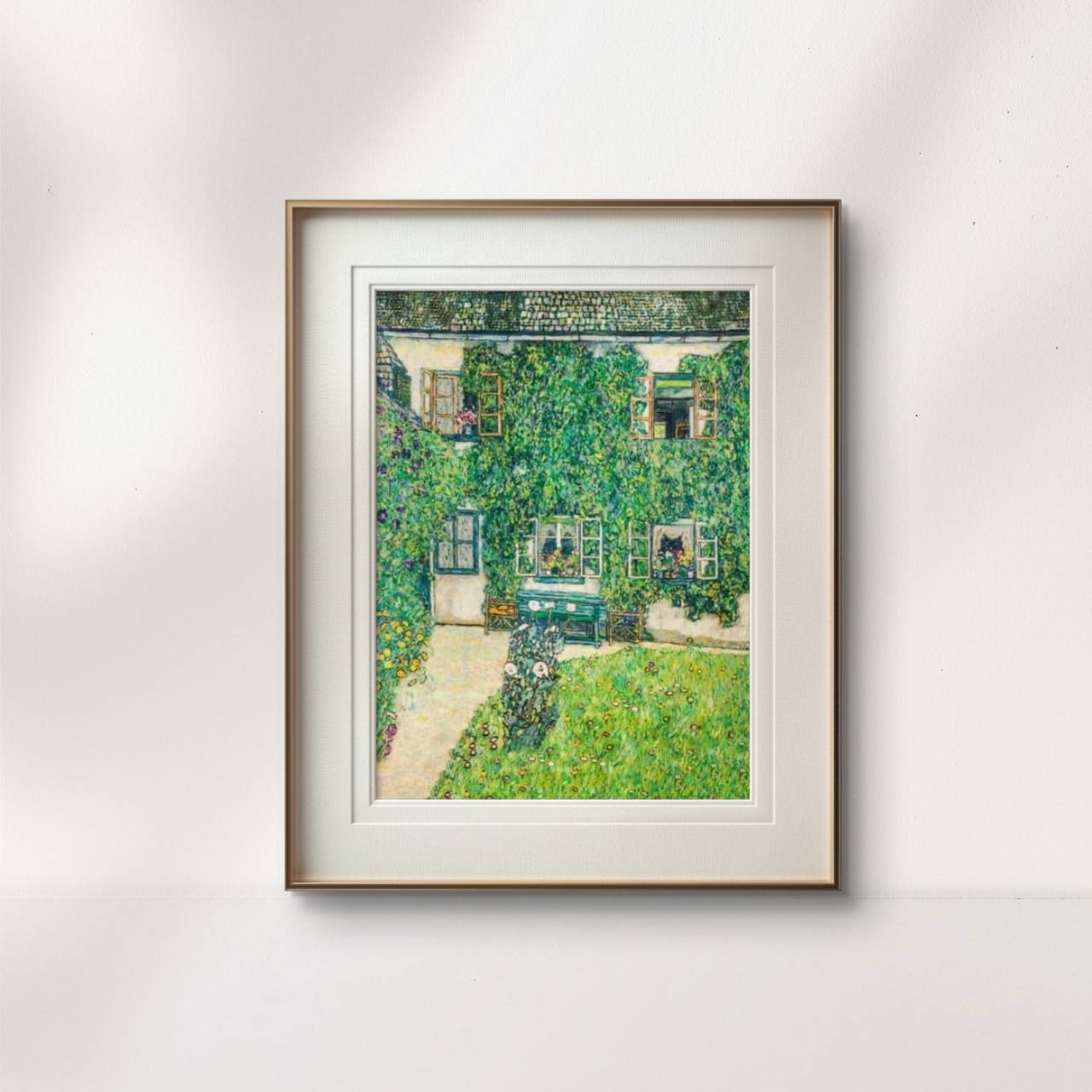 A framed painting of a house wrapped in vibrant green foliage, displayed against a light background. The detailed greenery and warm tones of the artwork add a serene, nature-inspired touch to the room.