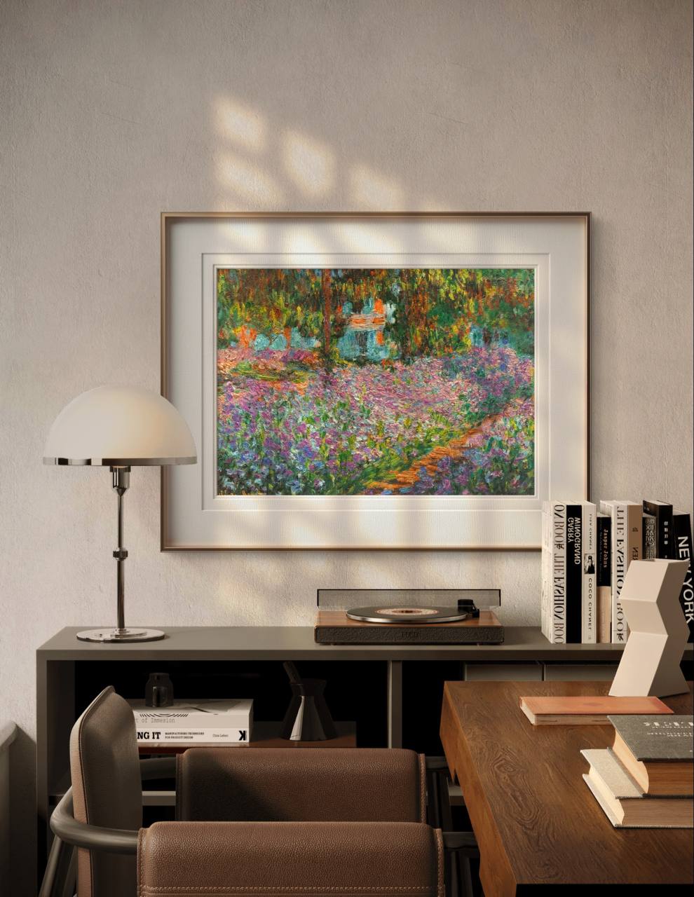 The framed painting is displayed above a modern desk, with a lamp and books nearby. Sunlight filters in, enhancing the warm and bright colors of the floral garden artwork in a cozy setting.
