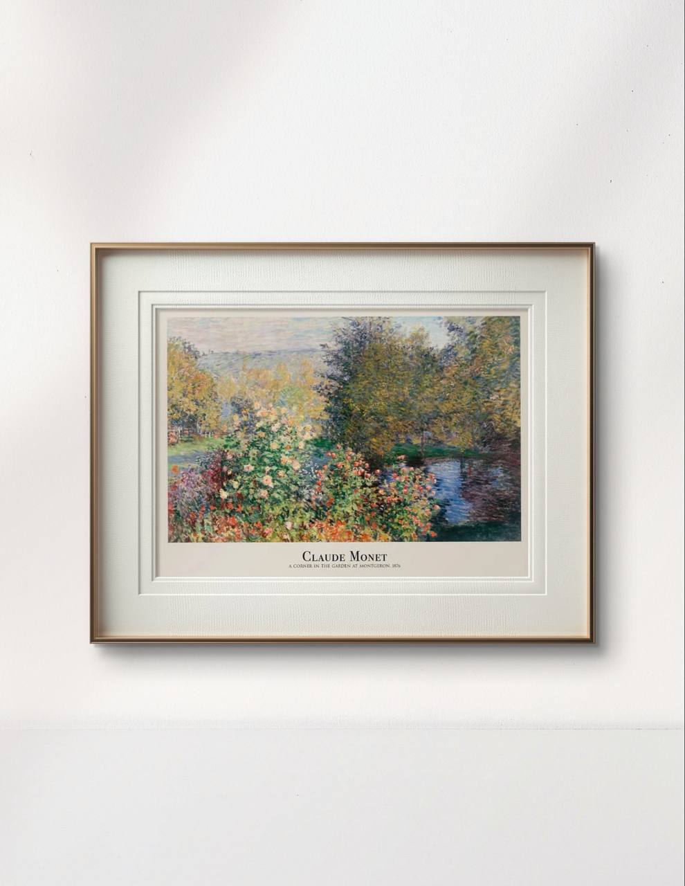 The same painting framed in a simple wooden frame with white matting, showing colorful flower beds and trees next to a reflective pond. The label beneath reads "Claude Monet – A Corner in the Garden at Montgeron, 1876.