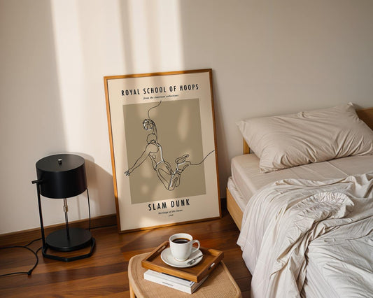 Framed artwork on a wall above a bed with a lamp and coffee cup on a side table.