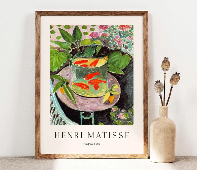 A still life painting of a glass bowl filled with bright orange goldfish, placed on a pink table, surrounded by green leaves and floral patterns. The background features lush vegetation and a decorative interior, with bold and expressive brushstrokes emphasizing color and contrast.