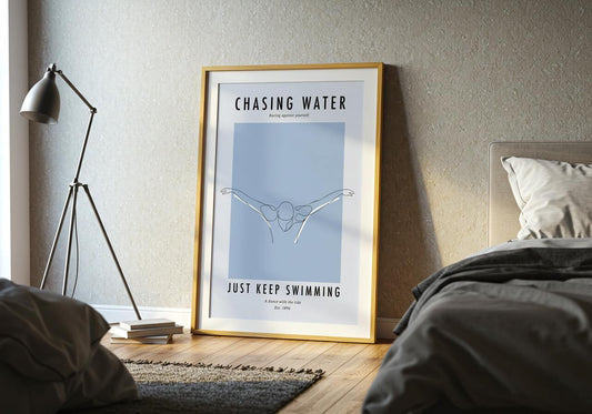 Framed poster titled 'Chasing Water' in a bedroom setting with a lamp and bed.