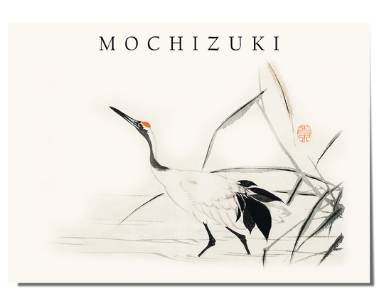A Japanese ink painting featuring a crane with a white body, black tail feathers, and a red marking on its head, walking alongside delicate reeds. The background is soft and minimal, with subtle brushstrokes creating a peaceful and flowing composition. The artwork includes a red seal and the word "Mochizuki" written in a simple, elegant font at the top, enhancing the traditional aesthetic.
