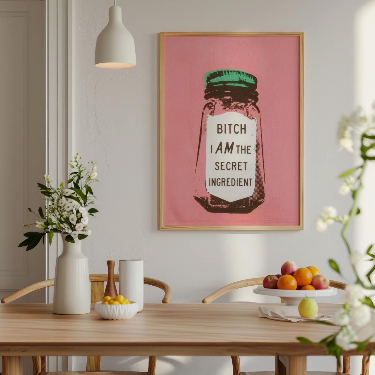 Dining room with a pink framed poster on the wall, table with fruits and decor items.
