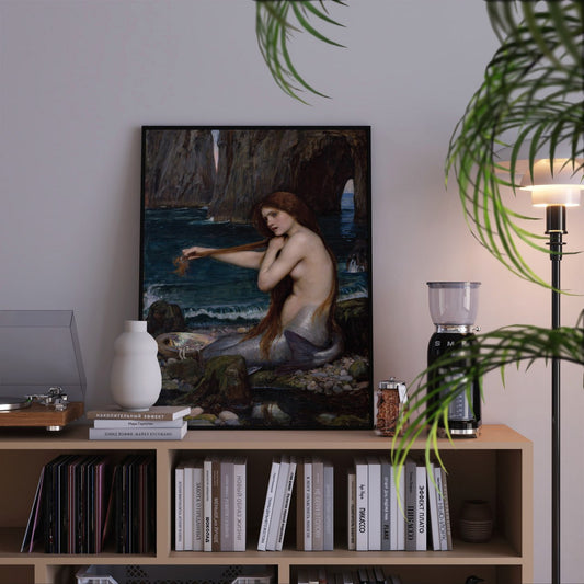 The painting features a beautiful mermaid seated on a rocky shore, partially submerged in the sea. She has long, flowing red hair that cascades down her back, and her upper body is bare, showcasing her graceful figure. The lower half of her body transitions into a shimmering tail, blending with the colors of the ocean.