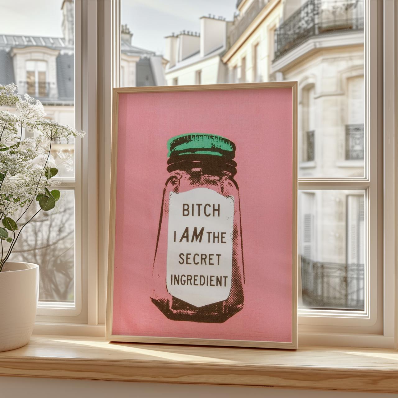 Framed artwork with a pink background and text on a windowsill.