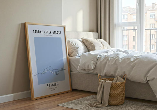 Framed artwork leaning against a wall in a bedroom with a bed and basket.