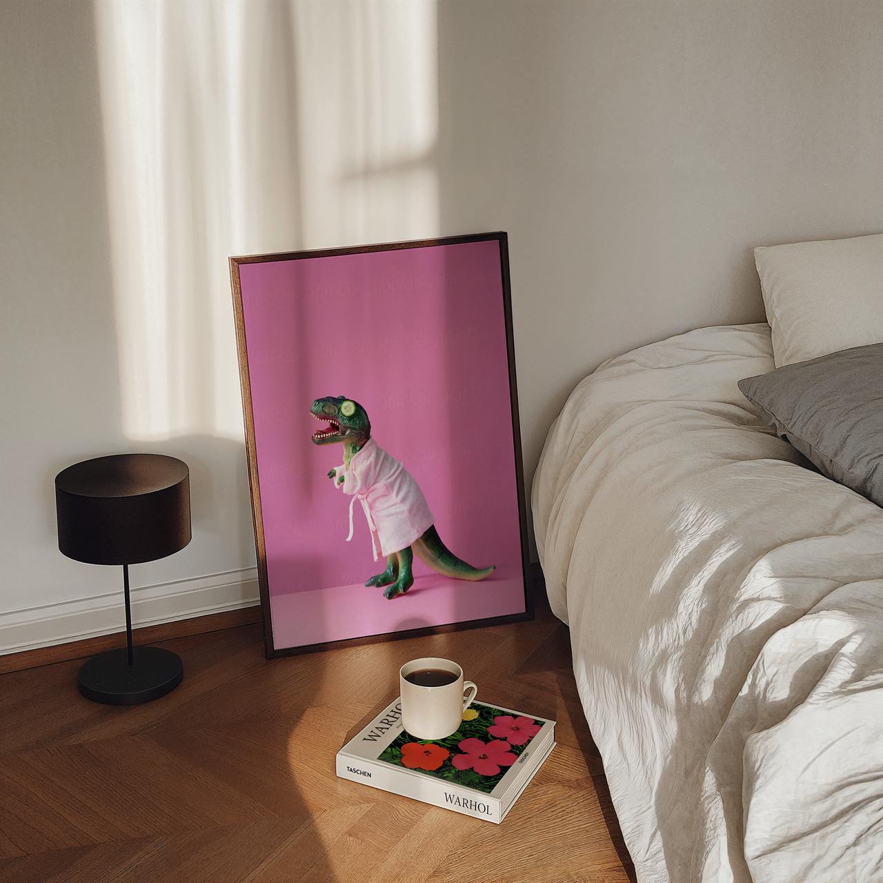 Framed picture of a dinosaur in a robe on a table next to a bed.