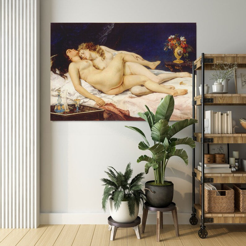 A classical oil painting featuring two nude women lying in an embrace on a bed with white and pink sheets. One woman has dark hair and rests on her back, while the other, with curly blonde hair, leans against her. A golden vase with red and white flowers sits on a nearby wooden table. The background is deep blue, contrasting with the warm skin tones and soft fabrics, creating a dramatic and intimate composition.