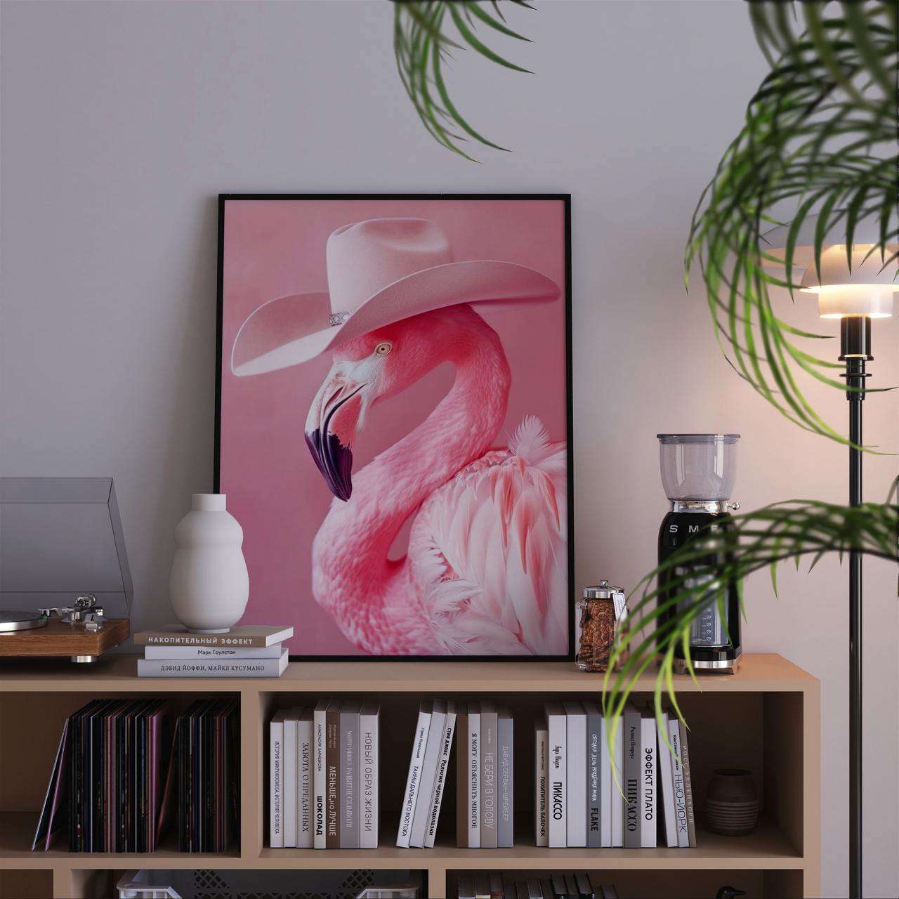 Framed artwork of a pink flamingo wearing a cowboy hat on a shelf with books and decor.