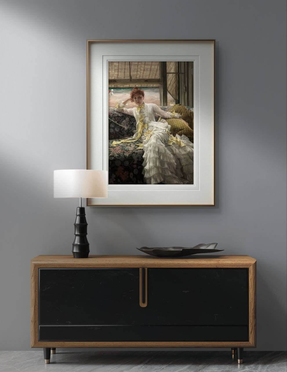 A modern interior setting with a wooden console table, a black table lamp, and a framed poster of "Seaside, July" by James Tissot hanging above. The wall art adds a sophisticated touch to the room, ideal for home decor and enhancing any living space with classic Victorian art.