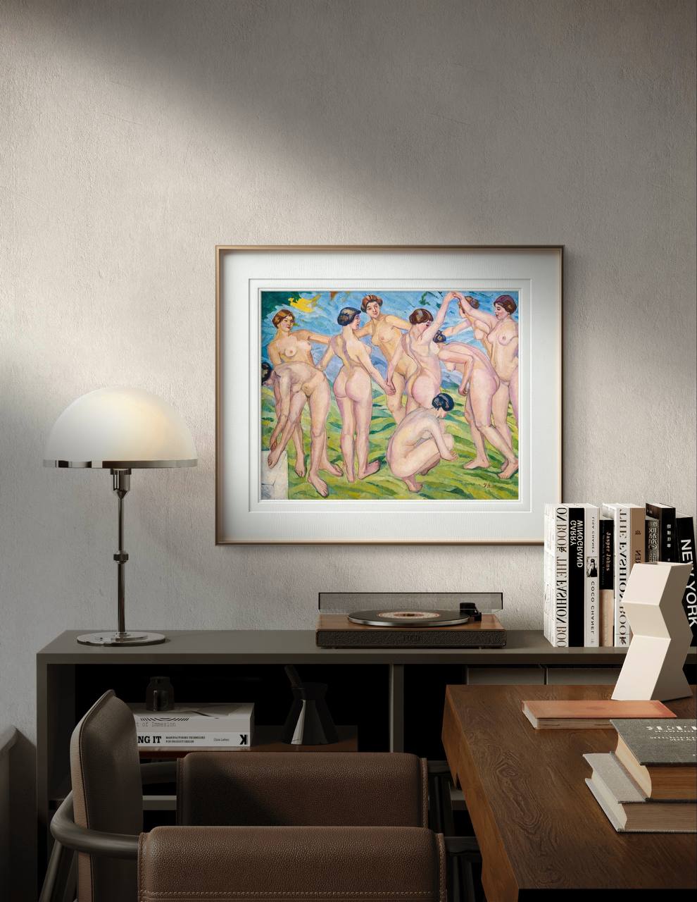 This lively painting features eight nude women engaging in a joyous dance on a green field. The women are connected in a circular formation, with a backdrop of a serene blue sky and abstract yellow birds. he poster is displayed in a modern room, above a dark wood sideboard adorned with books and a small lamp.