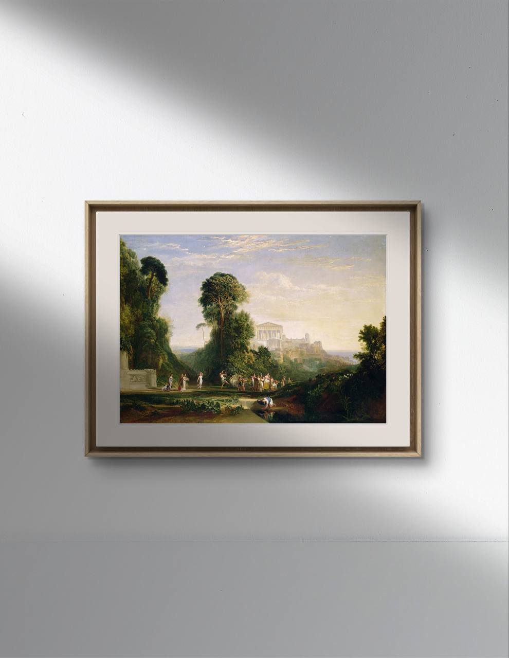 The second image presents another view of the same framed poster, this time hanging on a white wall. The frame is black with a minimalist design, giving a modern touch to the classical art reproduction. Natural light creates soft shadows on the wall, further highlighting the painting. The artwork shows a vibrant scene with classical figures in a green setting, with a majestic temple in the background.