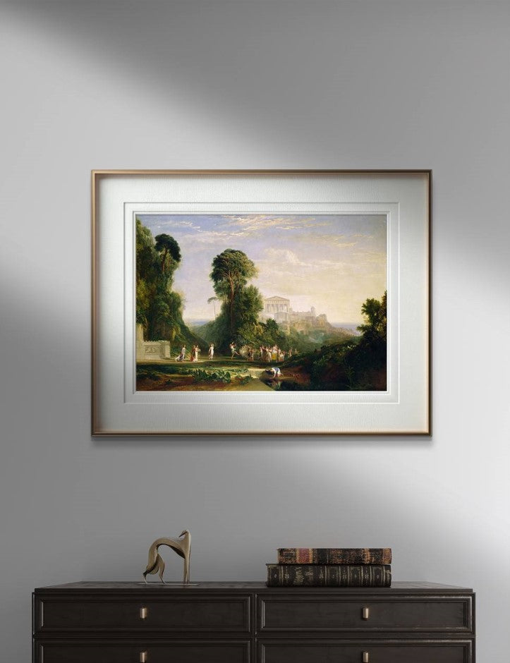 The poster is a reproduction of William Turner's painting "The Temple of Jupiter," depicting a classical landscape with ancient figures in a lush natural setting. In the background of the painting, a Greek temple is visible, surrounded by verdant vegetation and a clear sky. Below the painting, there is a table with several antique books stacked and a modern decorative sculpture.