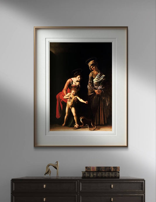 The third image presents the framed Caravaggio poster hanging on a gray wall above a dark wooden cabinet. The frame features a subtle golden edge, adding a touch of elegance to the display. The cabinet below holds antique books and a modern sculpture, creating a blend of classic and contemporary elements. The artwork’s deep shadows and vibrant highlights draw the viewer's eye, making it a focal point in the room.