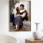 The second image features the same "Calinerie" poster framed and hanging on a white wall in a minimalist setting. The gentle lighting accentuates the tender moment captured in the painting, making it a charming addition to the room’s decor. The artwork’s soft colors and realistic details are beautifully reproduced