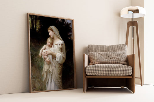 The first image features a framed poster of William Bouguereau's painting "Innocence." The artwork depicts a serene scene of a woman holding a baby and a lamb. The woman, draped in soft white and beige garments, looks down tenderly at the baby, who is peacefully sleeping in her arms alongside the lamb. The background shows a tranquil, wooded area. The framed poster leans against a wall next to a modern chair and lamp, creating a harmonious blend of classic art and contemporary decor.