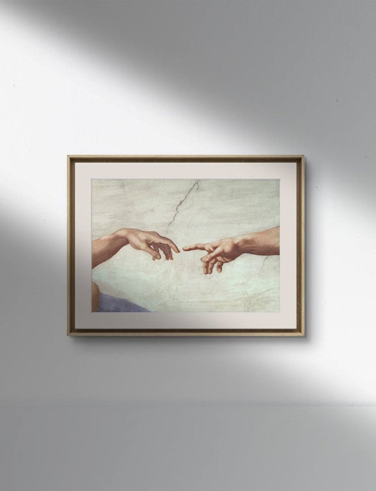 The second image shows the same "The Creation of Adam" hands poster framed and hung on a white wall. The classical frame and soft lighting emphasize the iconic moment captured by Michelangelo. The high-quality reproduction highlights the detailed depiction of the hands and the background, making it an elegant addition to any decor.