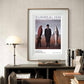 A framed surrealist poster hangs above a desk with books and a vinyl player. The man in a suit stands between a red bird and a fish. The scene blends modern decor with artistic flair