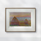 A framed Monet print of haystacks at sunset. The soft pink and orange sky contrasts with the earthy tones of the haystacks. The simple frame highlights the serene artwork
