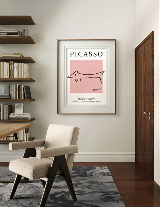 A Picasso poster with a minimalist dachshund drawing hangs in a cozy room. The modern furniture and neutral tones create a sophisticated setting for the artwork