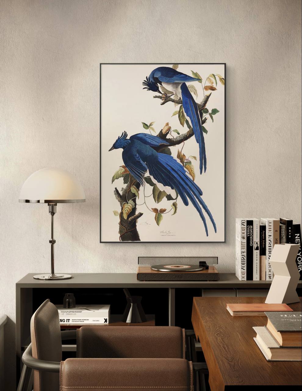 A framed vintage print of two bright blue birds perched on a branch, displayed in a modern room. The intricate details and rich colors of the birds contrast beautifully with the minimalist decor