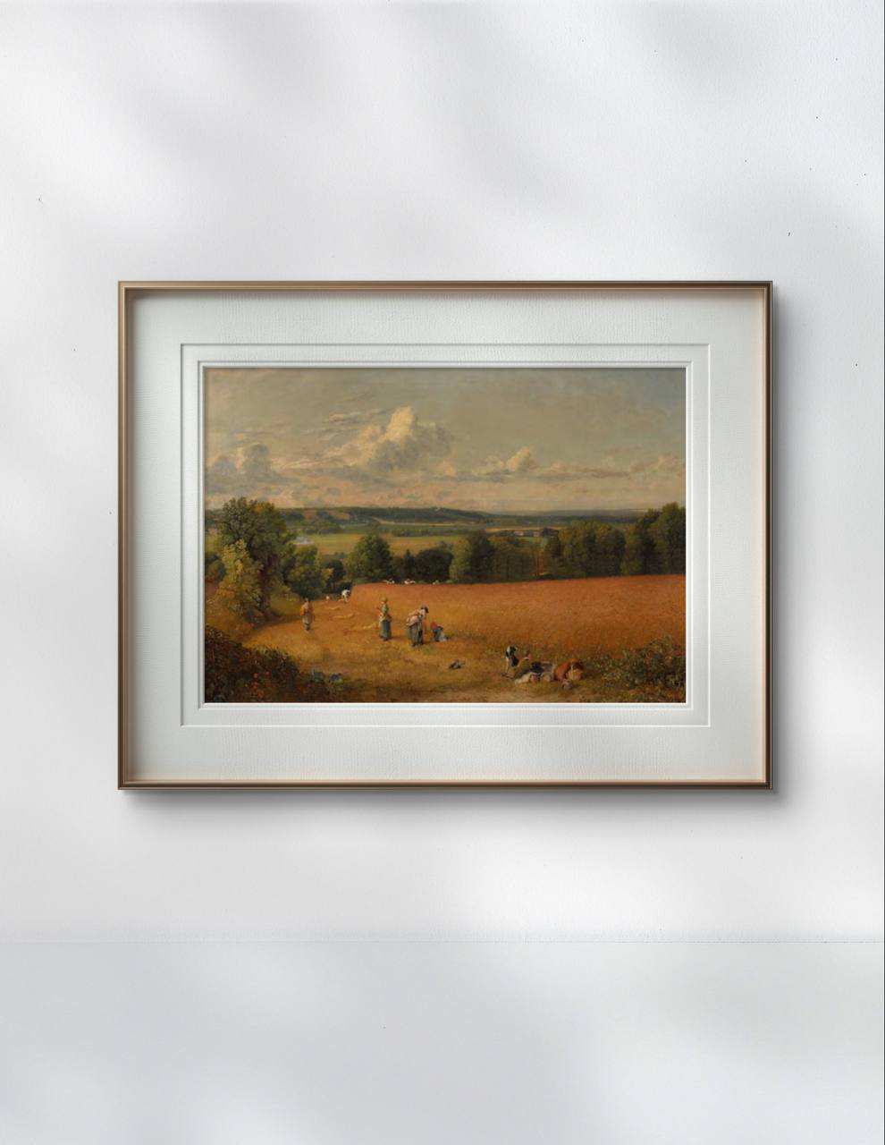 A framed John Constable painting of a wheat field and workers is displayed in a cozy study. The golden hues of the wheat blend harmoniously with the room's natural decor.