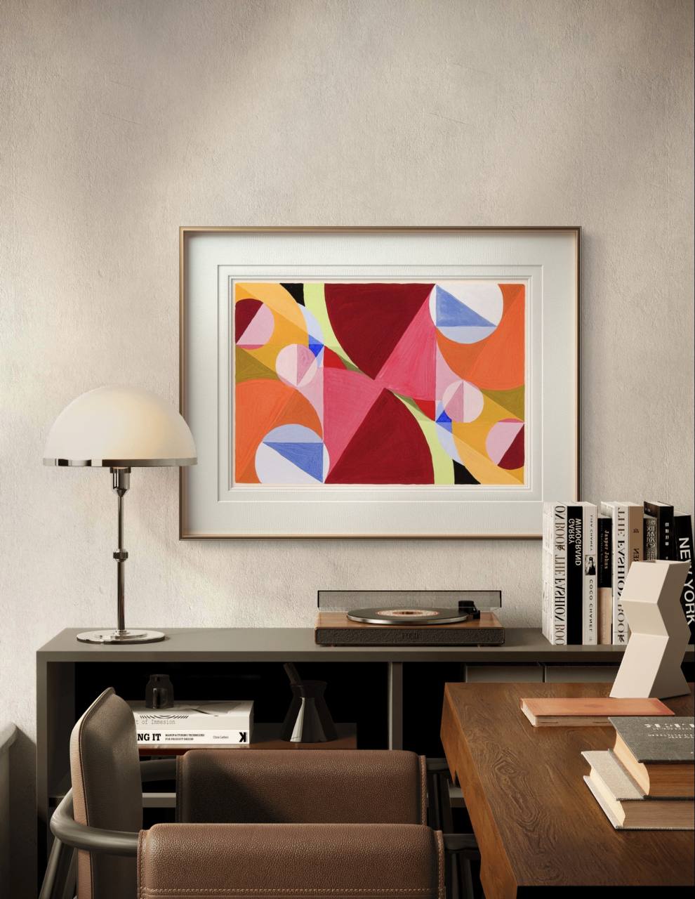 A framed abstract print with bright geometric shapes in red, pink, and orange. The bold colors and dynamic design bring energy and modern style to the room's neutral decor.