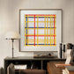 A framed abstract print with intersecting red, blue, and yellow lines. The geometric design adds a striking modern touch to the minimalist decor of the room