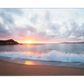 A serene beach scene with gentle waves crashing onto the shore at sunset. The sky is painted with soft clouds, and the horizon glows in vibrant orange and pink tones as the sun sets.