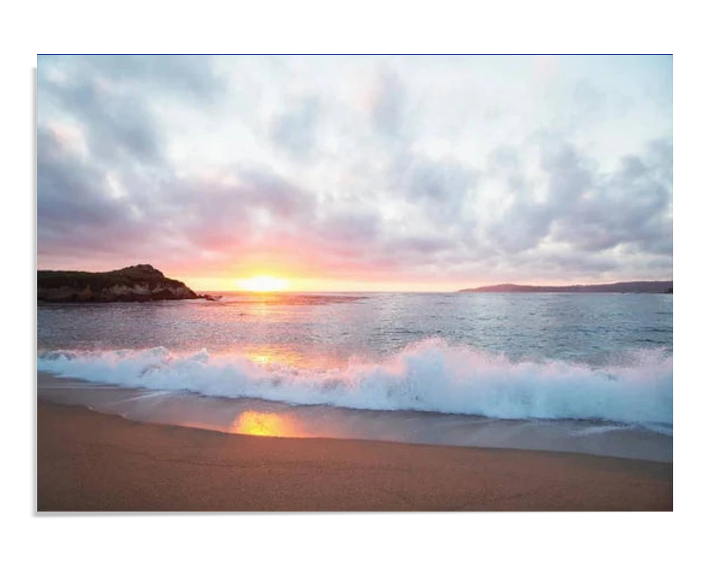 A serene beach scene with gentle waves crashing onto the shore at sunset. The sky is painted with soft clouds, and the horizon glows in vibrant orange and pink tones as the sun sets.