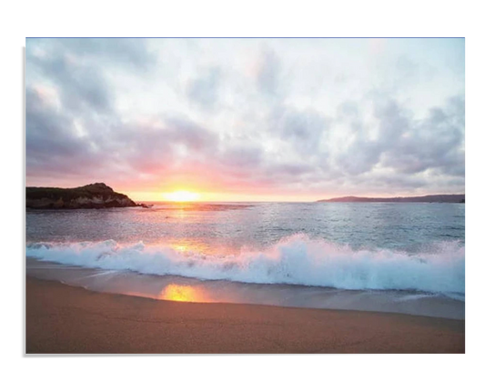 A serene beach scene with gentle waves crashing onto the shore at sunset. The sky is painted with soft clouds, and the horizon glows in vibrant orange and pink tones as the sun sets.