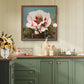 The same framed pink peony artwork is shown hanging on a light green kitchen wall. Below it is a wooden countertop with kitchen decor, including a vase of flowers, cutting boards, and plates, blending modern design with floral elegance.