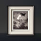 A framed monochrome painting of a nude woman riding a broomstick through the clouds, her hair blowing wildly in the wind. The soft shading and ethereal clouds create a mystical, timeless scene, adding a vintage charm to the room.