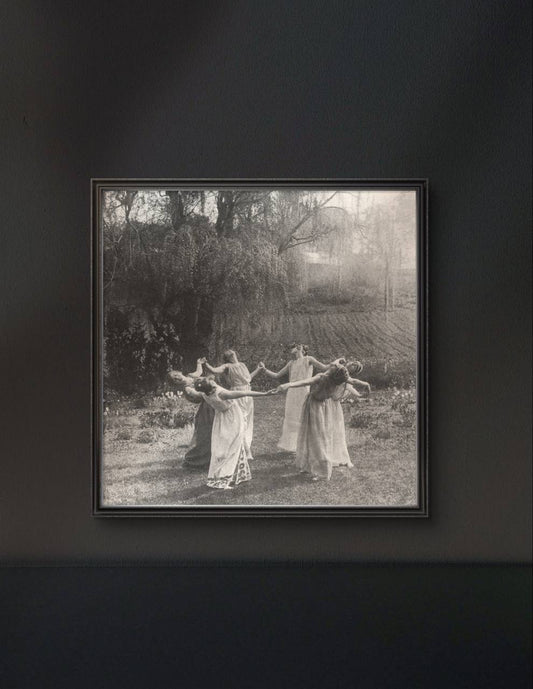 The framed artwork, set against a dark wall, enhances the ethereal quality of the vintage photograph. The contrast between the light dancers and the dark background creates a sense of mystery and enchantment.