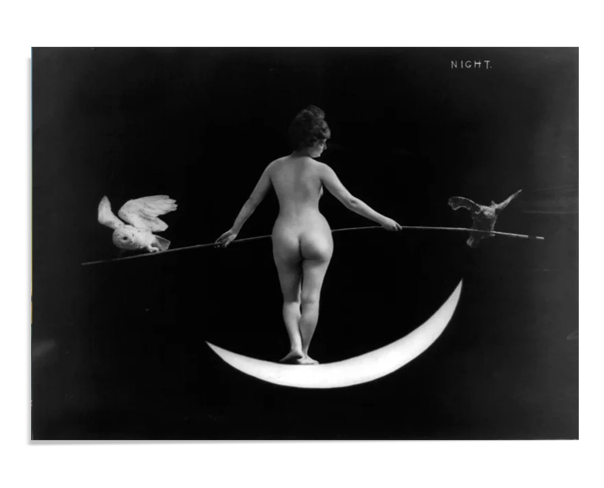 A black-and-white image of a nude woman balancing on a crescent moon, holding a pole with an owl on one side and a bat on the other. The minimalistic composition, titled "Night," exudes a sense of ethereal beauty and mystery.