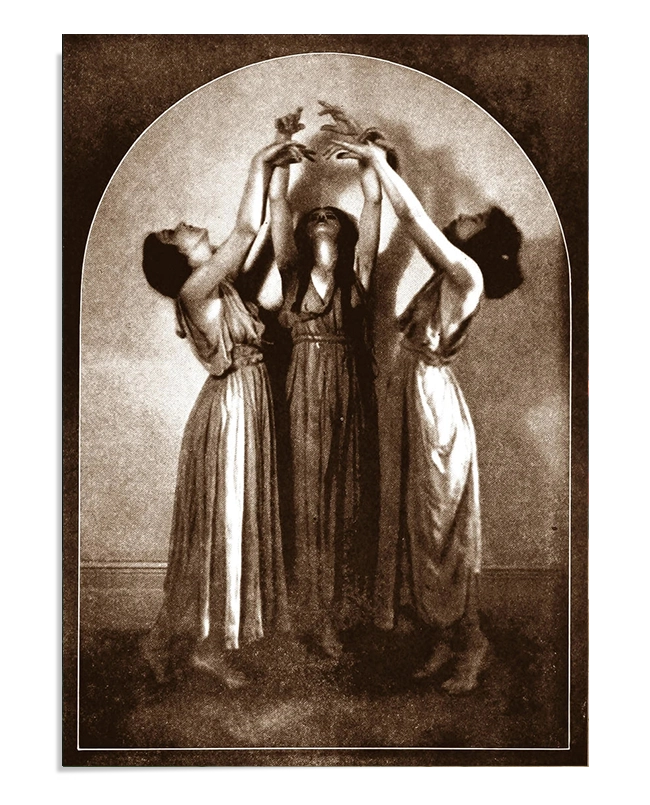 Three women in flowing dresses stand in a circle, their arms raised and hands intertwined, as if engaged in a mystical ritual or dance. The sepia tones and soft lighting evoke an air of enchantment and mystery.