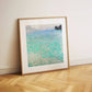  A framed painting of a peaceful lake scene, leaning against a white wall. The water's turquoise hues stand out, reflecting light beautifully, and the artwork's simplicity brings a calming effect to the minimalist space.