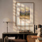 The framed mountain scene is displayed in a cozy, modern room with soft sunlight illuminating the space. The majestic peaks and peaceful valley create a sense of tranquility and awe in the setting.
