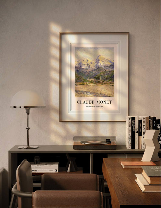 The framed mountain scene is displayed in a cozy, modern room with soft sunlight illuminating the space. The majestic peaks and peaceful valley create a sense of tranquility and awe in the setting.