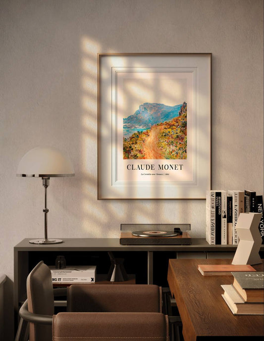 The framed artwork is showcased in a contemporary room, bathed in soft sunlight. The bright landscape of mountains, flowers, and path adds a sense of warmth and nature to the clean, modern space.