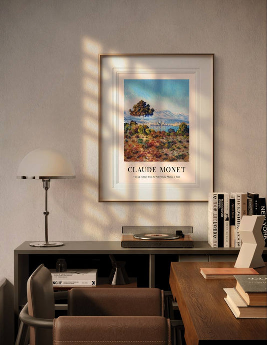 In a cozy, modern room, the framed "View of Antibes" is displayed with soft light casting a warm glow on the painting. The piece enhances the calm atmosphere of the room with its peaceful, natural tones.