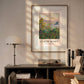The Monet "Flower Beds at Vétheuil" poster, framed and hanging above a desk, is softly illuminated by sunlight in a cozy, modern room with books and a lamp.