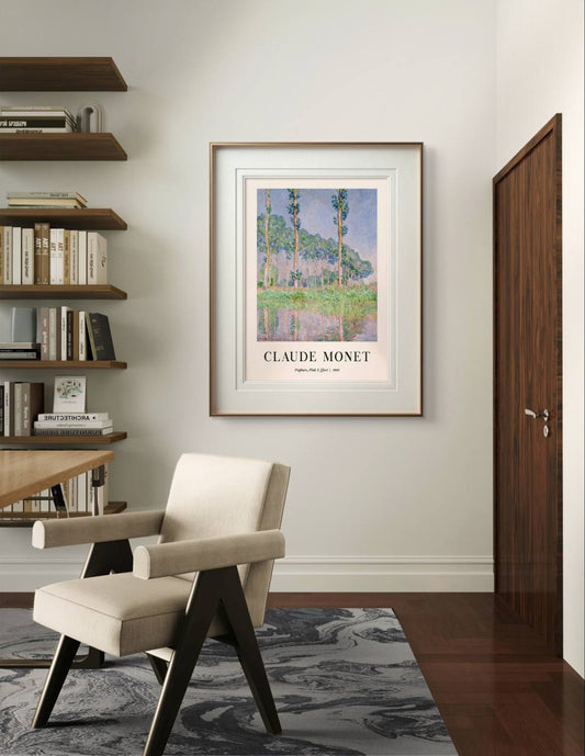 A framed Monet poster, "Poplars, Pink Effect," hangs on a modern wall near a cozy chair and shelves filled with books, giving the space a serene and artistic feel.